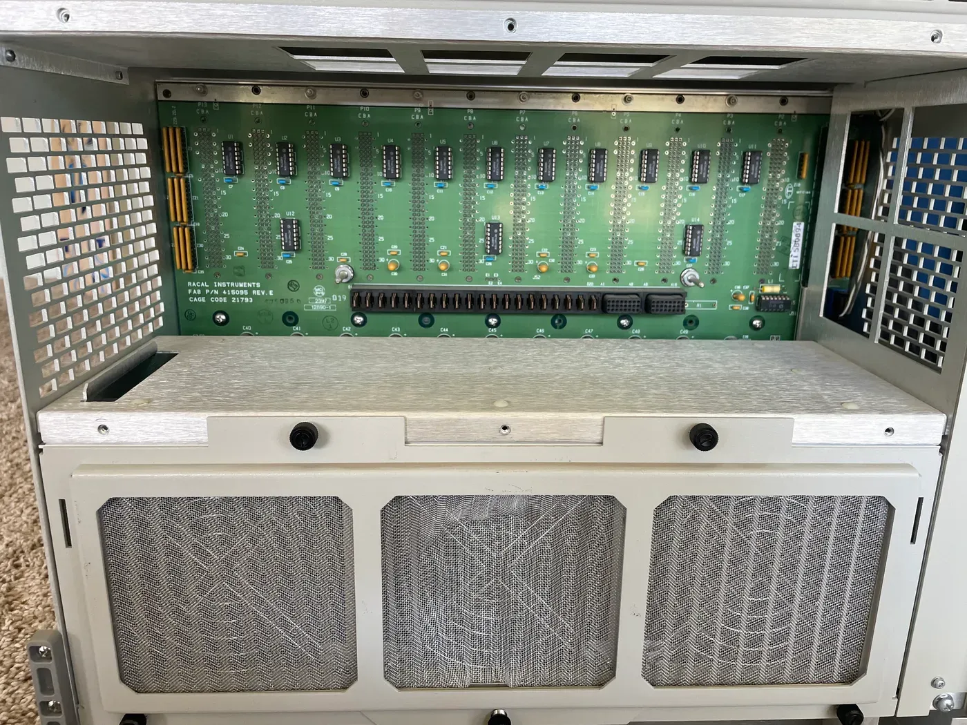 Rear of a Racal 1261B VXI mainframe showing the three-fan fault-tolerant cooling assembly below the backplane