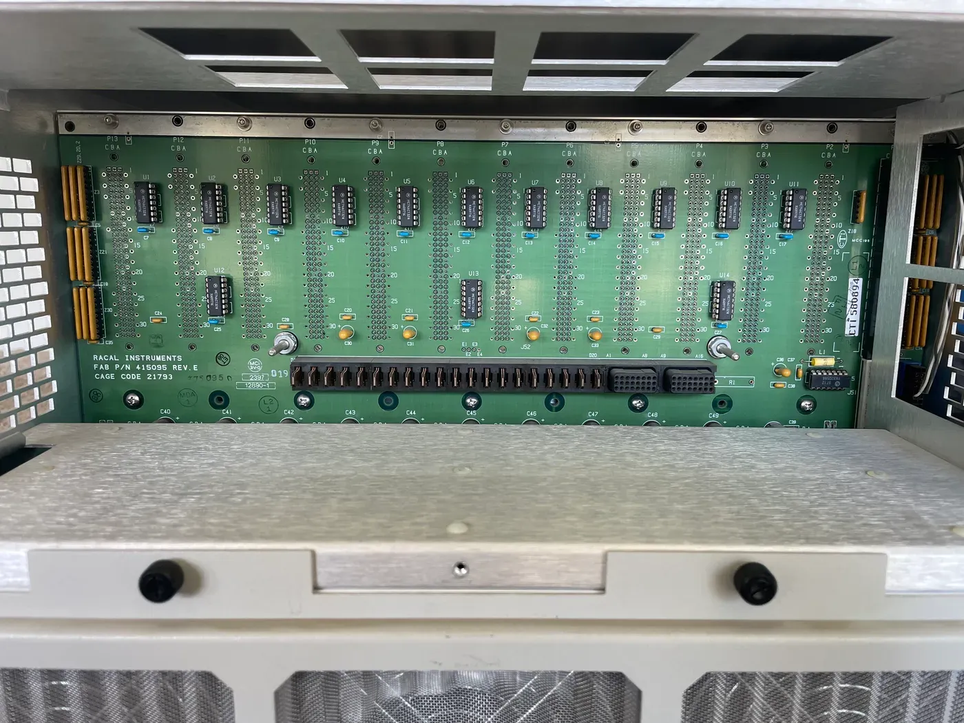 Racal 1261B VXI backplane viewed from the rear of the chassis, showing the slot connectors and the Racal Instruments fab part number 415095 Rev E with CAGE code 21793